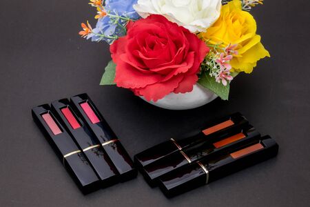 Lipstick and flowers with cosmetics for women To make her look beautiful at work on a black background.の写真素材