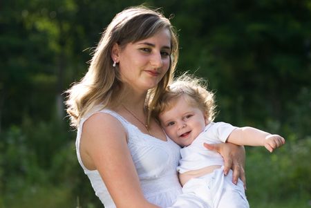 A young attractive woman holds her little cute baby in his handsの写真素材