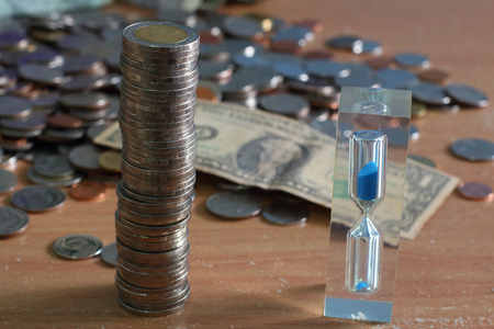Money and hourglass on the table