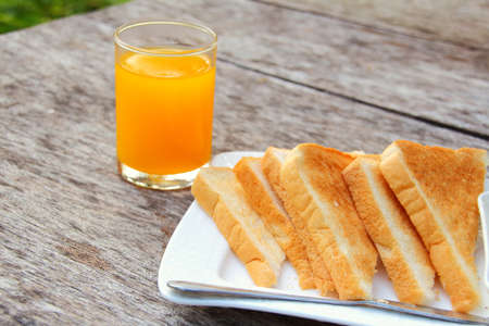 orange juice and bread on the tableの写真素材