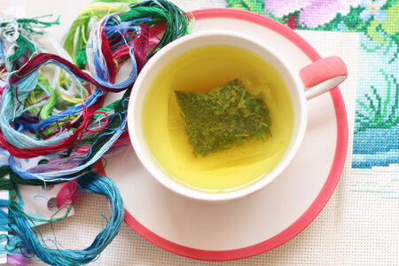 Hot tea and cross stitch  placed on the table.の写真素材