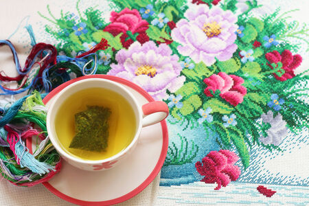 Hot tea and cross stitch  placed on the table.の写真素材
