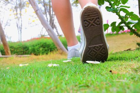 People wearing white sneakers are moving in the grass