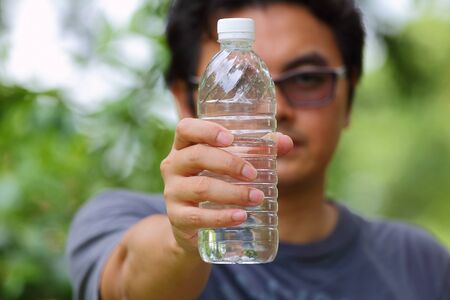 asain man drinking water in the parkの写真素材