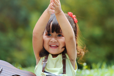 Little asian girl was clapping happily in the park