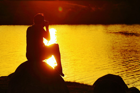 Man sitting on rock, silhouetteの写真素材