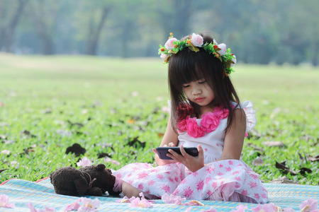 Cute Asian girl smiling and talking on her cell phone in the parkの写真素材