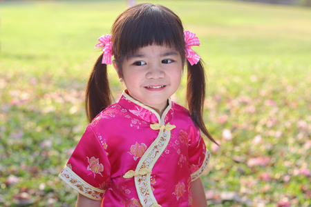 Portrait, Little asian girl in pink qipao was smiling and playing happily in the parkの写真素材