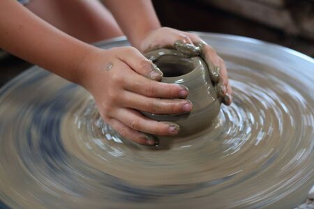 A child's hand potter making a clay pot in thailandの写真素材