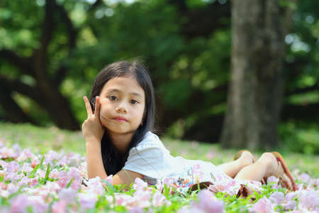 Portrait, asian girl was lying on the grass in the park and look at cameraの写真素材
