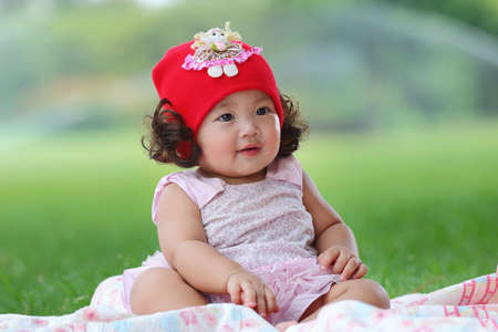 Little asian girl wearing a red hat was playing happily and smiling in the park, close upの写真素材