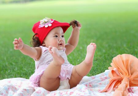 Little asian girl wearing a red hat was playing happily and smiling in the park, close upの写真素材