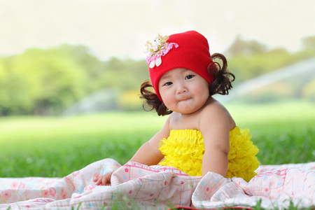 Little asian girl wearing a red hat was playing happily and smiling in the park, close upの写真素材