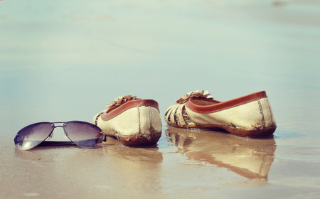 Sunglasses and shoes lay on the sand at the beach, vintage toneの写真素材
