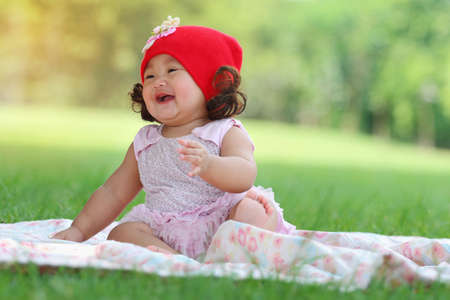 Little asian girl wearing a red hat was playing happily and smiling in the park, close upの写真素材