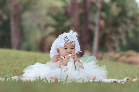 Little asian girl wearing a white dress was playing happily and look at the camera in the park, close upの写真素材