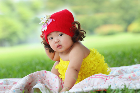 Little asian girl wearing a red hat was playing happily and smiling in the park, close upの写真素材
