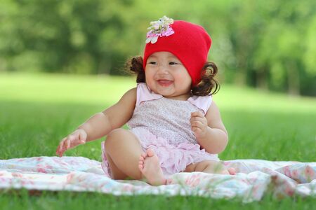 Little asian girl wearing a red hat was playing happily and smiling in the park, close upの写真素材