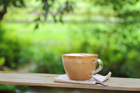 Hot coffee cup resting on a wooden board in nature.の写真素材
