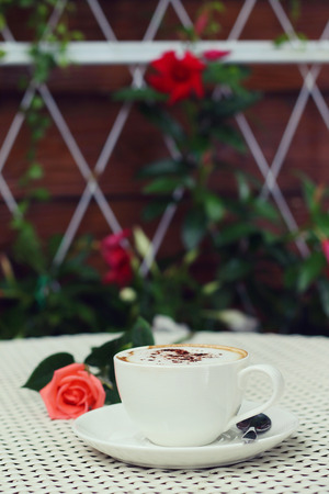 Hot coffee cup and rose on a white table.の写真素材