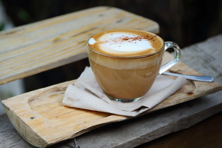 Hot coffee cup resting on a wooden board.の写真素材