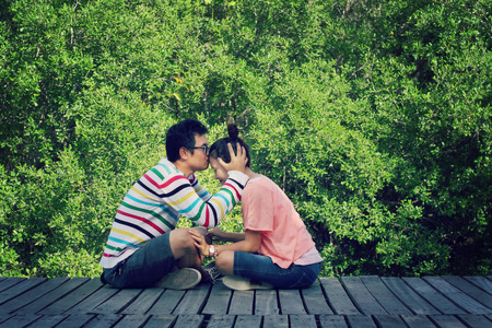 Two lovers sitting on the bridge, Man kissing the forehead of the woman he loves.の写真素材
