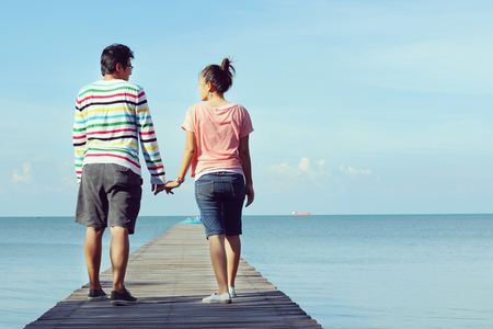 Two lovers walking on the bridge at the sea and holding themselves by hands.の写真素材