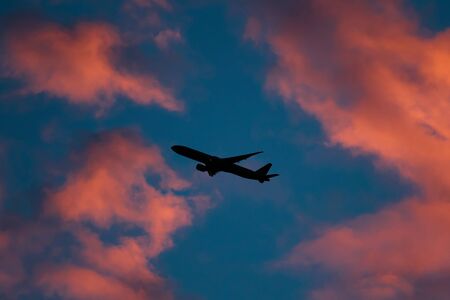 Silhouette, a plane on the sky at the sunsetの写真素材