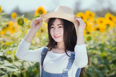 Outdoor portrait in the sunflowers garden, teenage asian girl wearing a hat.の写真素材