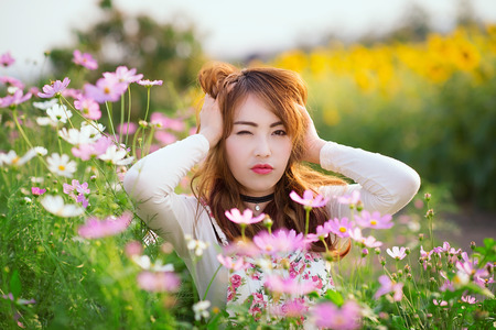 Outdoor portrait in the cosmos garden, teenage asian girl wearing a hat.の写真素材
