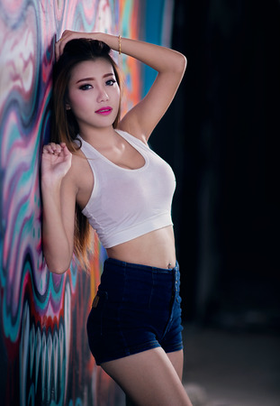 Sexy girl in white vest wiht jeans shorts and graffiti wallの写真素材