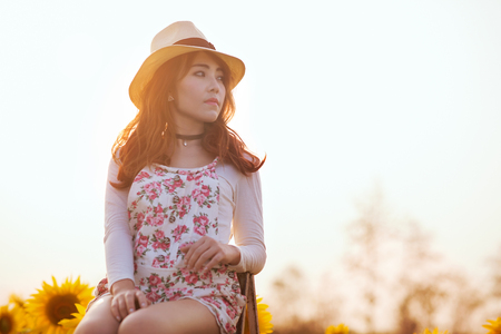 Outdoor portrait in the sunflowers garden, teenage asian girl wearing a hat and the sunsetの写真素材