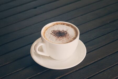 Cappuccino, Hot coffee cup on a wooden table, vintage tone and soft focus