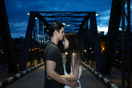 Young couple in love on the bridge at night timeの写真素材
