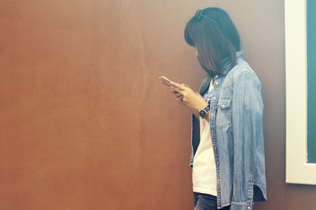 woman in jeans shirt and jeans using smartphone, vintage toneの写真素材