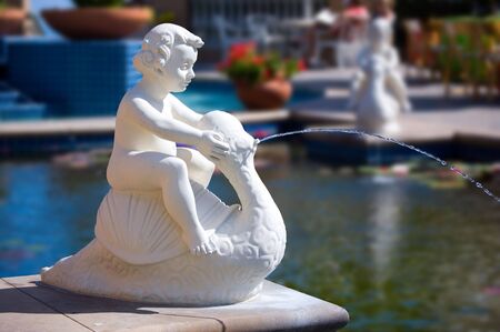 Cherub Fountain next to pool of water.の写真素材