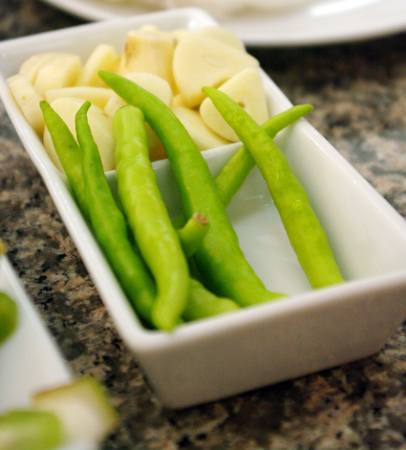 green chili peppers and garlic cloves on a plateの写真素材