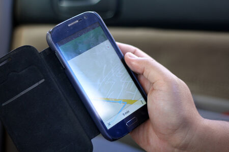man hand holding a smart phone with a GPS navigator on the screen.