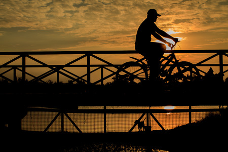 silhouette of biker on Bridge at sunsetの写真素材