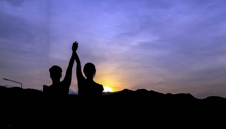 Silhouette of a man Happy successful raising arms to the sky on lighting sunsetの写真素材