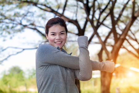 Athletic woman asia warming up and Young female athlete sitting on an exercising and stretching in a park before Runner outdoor on summer, healthy lifestyle conceptの写真素材