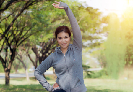 Athletic woman asia warming up and Young female athlete sitting on an exercising and stretching in a park before Runner outdoor on summer, healthy lifestyle conceptの写真素材