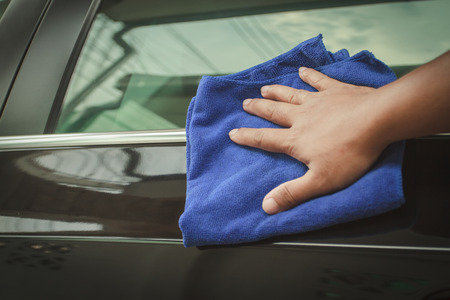 Hand with microfiber cloth cleaning black car.の写真素材