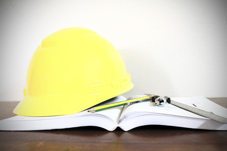 hard hat with pencil compasses and rulers/book on table and wallの写真素材