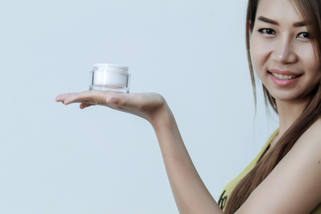 A beautiful woman asia using a skin care product, moisturizer or lotion and Skincare  taking care of her dry complexion. Moisturizing cream in female hands .の写真素材