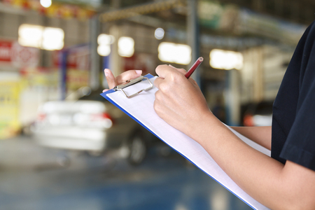 Portrait of smiling young female mechanic inspecting on a car in auto repair shopの写真素材