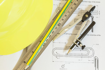 hard hat with pencil compasses and rulers/book on table and wall
