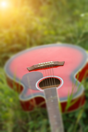 blurry and soft focus of guitar on grass at sunset.