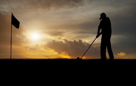 silhouette of golfers hit sweeping and keep golf course in the sunsetの写真素材