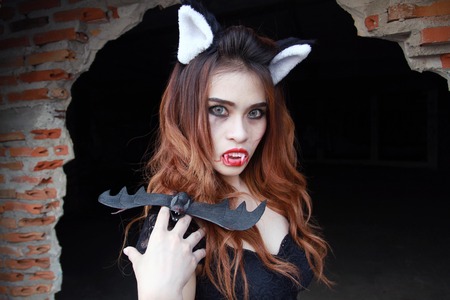 Beautiful Young woman as sexy vampire - halloween portrait on dark backgroundの写真素材